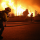 Firefighters work on a house fire during the Saddleridge Fire in the early morning hours on October 11, 2019 in Porter Ranch, California.
